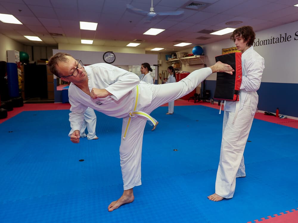 an old guy and a young lady pair for a taekwondo kicking practice in Norristown PA