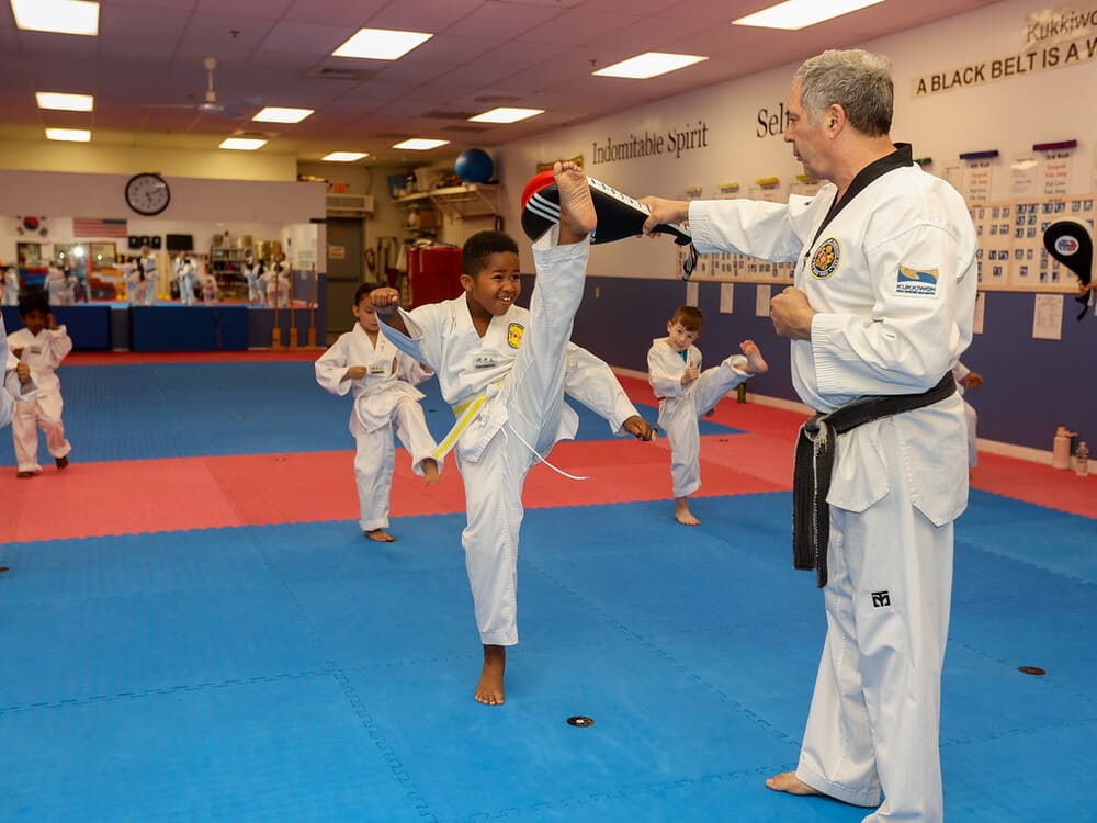 a group of kids practice taekwondo kick with their master in Norristown PA