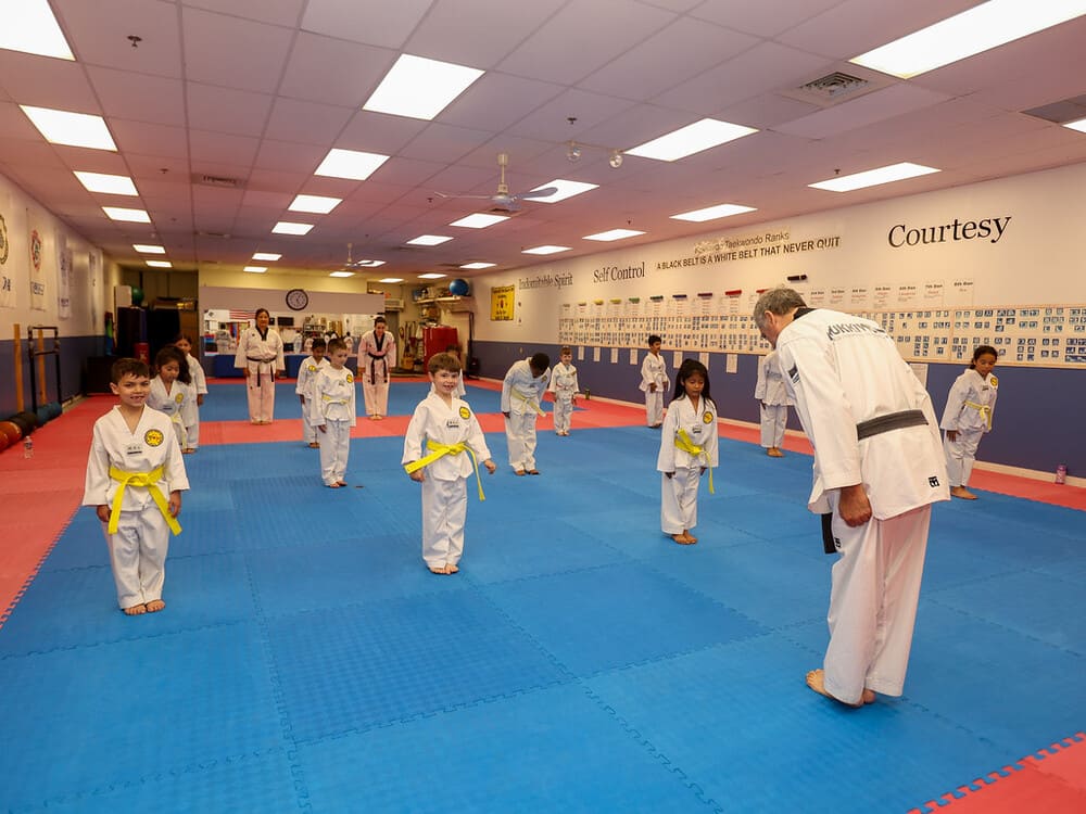 a group of kids in taekwondo uniform bow down before taekwondo class